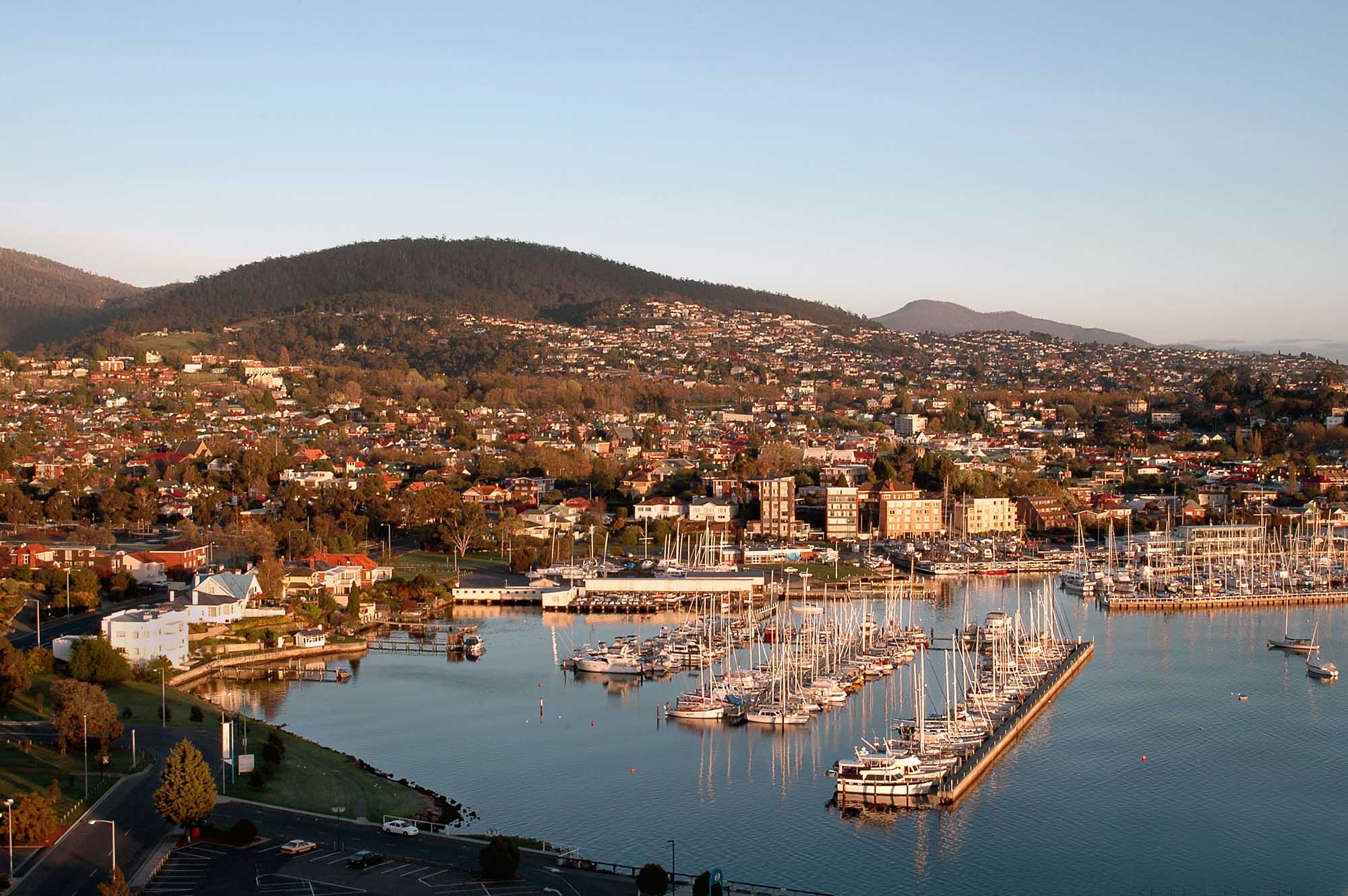Waterfront Marina and Hillside City Vista A scenic aerial view of a coastal city with a well-organized marina filled with sailboats in