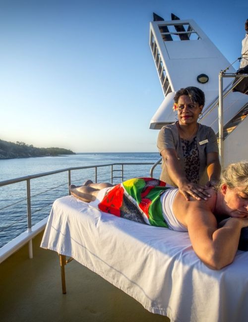 A passenger receives an on-deck massage while aboard a Blue Lagoon Cruises vessel, with serene blue