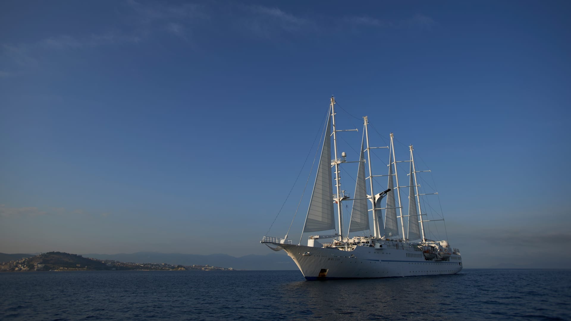 Windstar Cruises Luxury Sailing Ship at Anchor A striking white multi-masted sailing ship anchored in clear blue Mediterranean waters, with